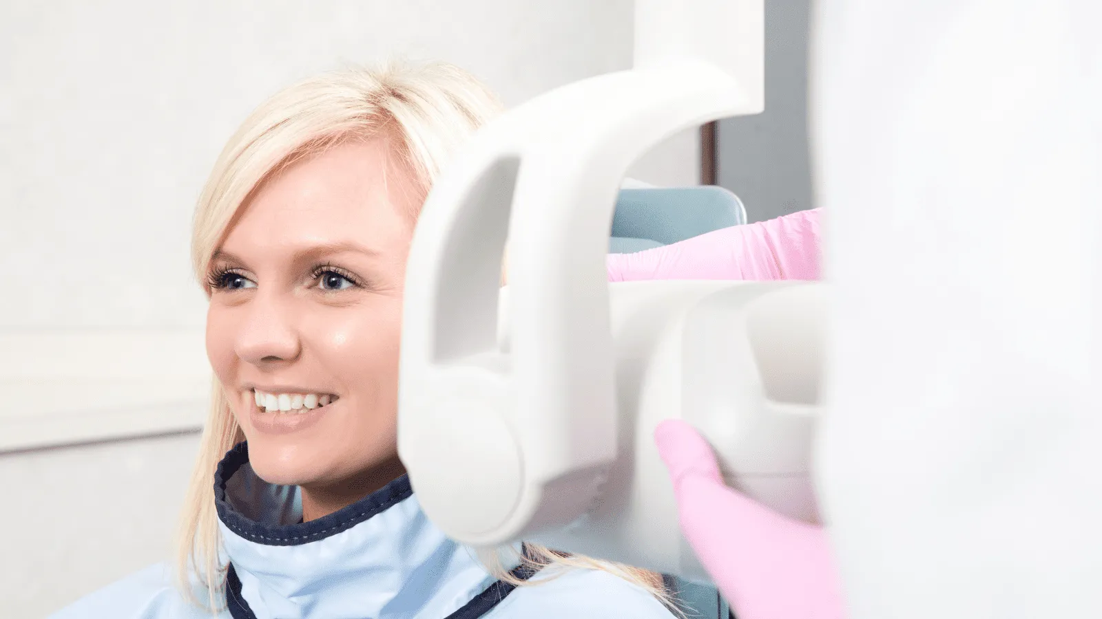 Paciente sonriendo mientras se realiza una radiografía panorámica dental